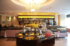 A hotel lobby with a central buffet table, a chandelier, and a bar area with shelves of bottles. - Dongfang Tanggula Hotel (High-speed Railway Station) (Dongfang)
