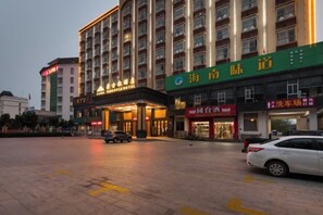 A hotel with multiple floors, a covered entrance, and various shops on the ground floor.