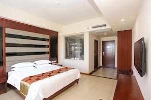 A hotel room with a bed, a TV, a large window, and a door leading to another room. - Dongfang Tanggula Hotel (High-speed Railway Station) (Dongfang)