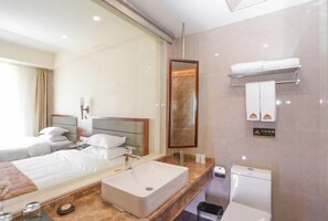 A hotel room with a large mirror, a sink, a toilet, and two beds. - Dongfang Tanggula Hotel (High-speed Railway Station) (Dongfang)
