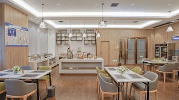 A modern dining area with wooden flooring, tables, chairs, pendant lighting, and a central island with a counter.