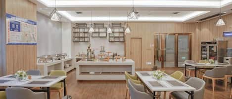 Un comedor moderno con suelo de madera, mesas, sillas, iluminación colgante y una isla central con mostrador.