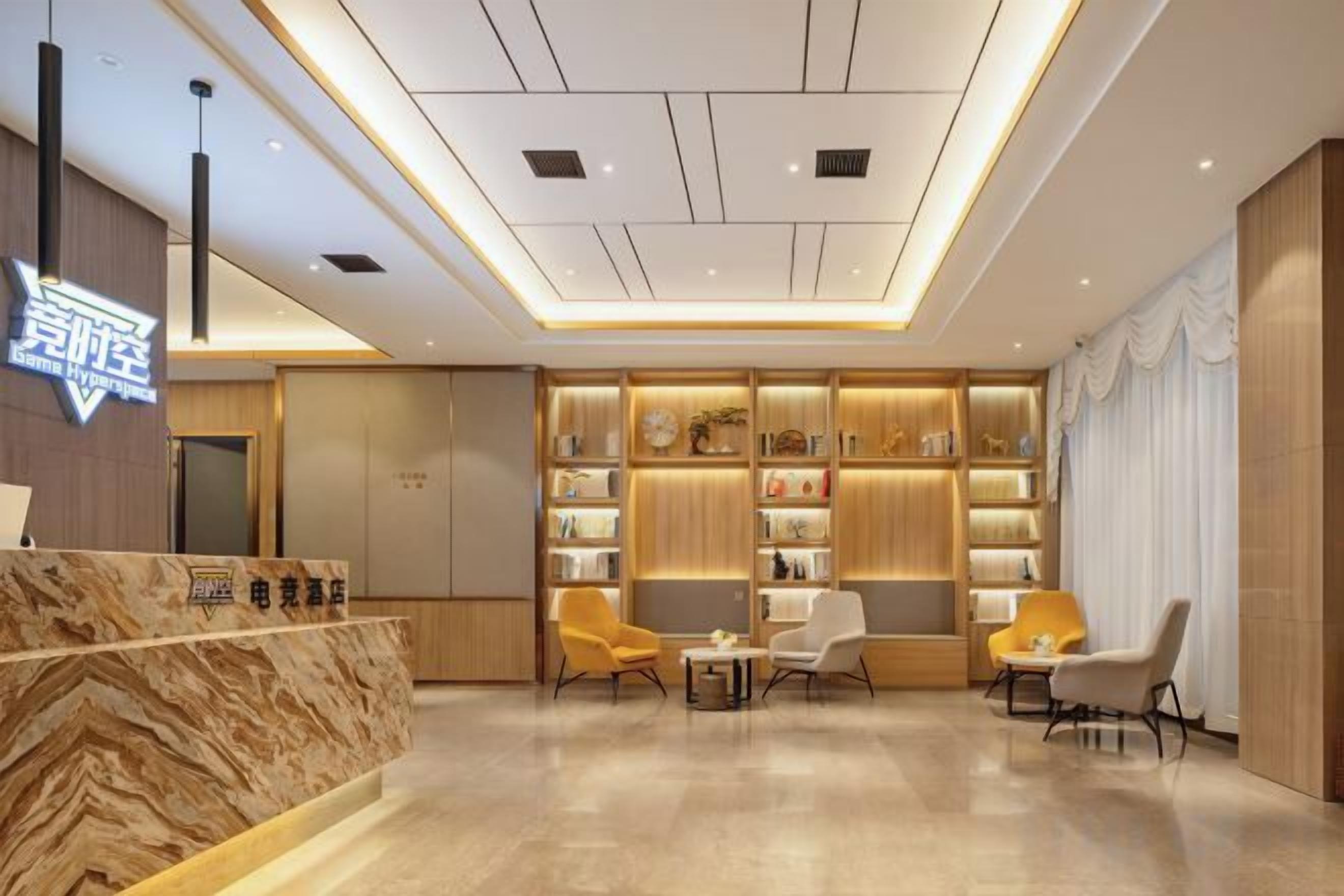 A hotel lobby with a reception desk, seating area, and a wall with shelves.