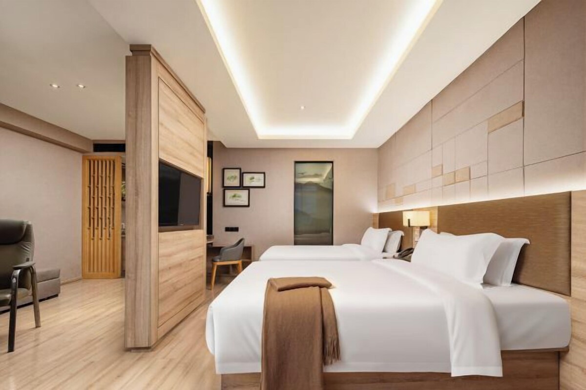A modern hotel room with a large bed, a desk, and a TV.