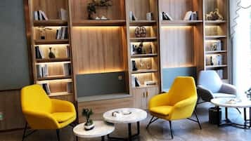 A modern library with bookshelves, two yellow armchairs, and a small round table.