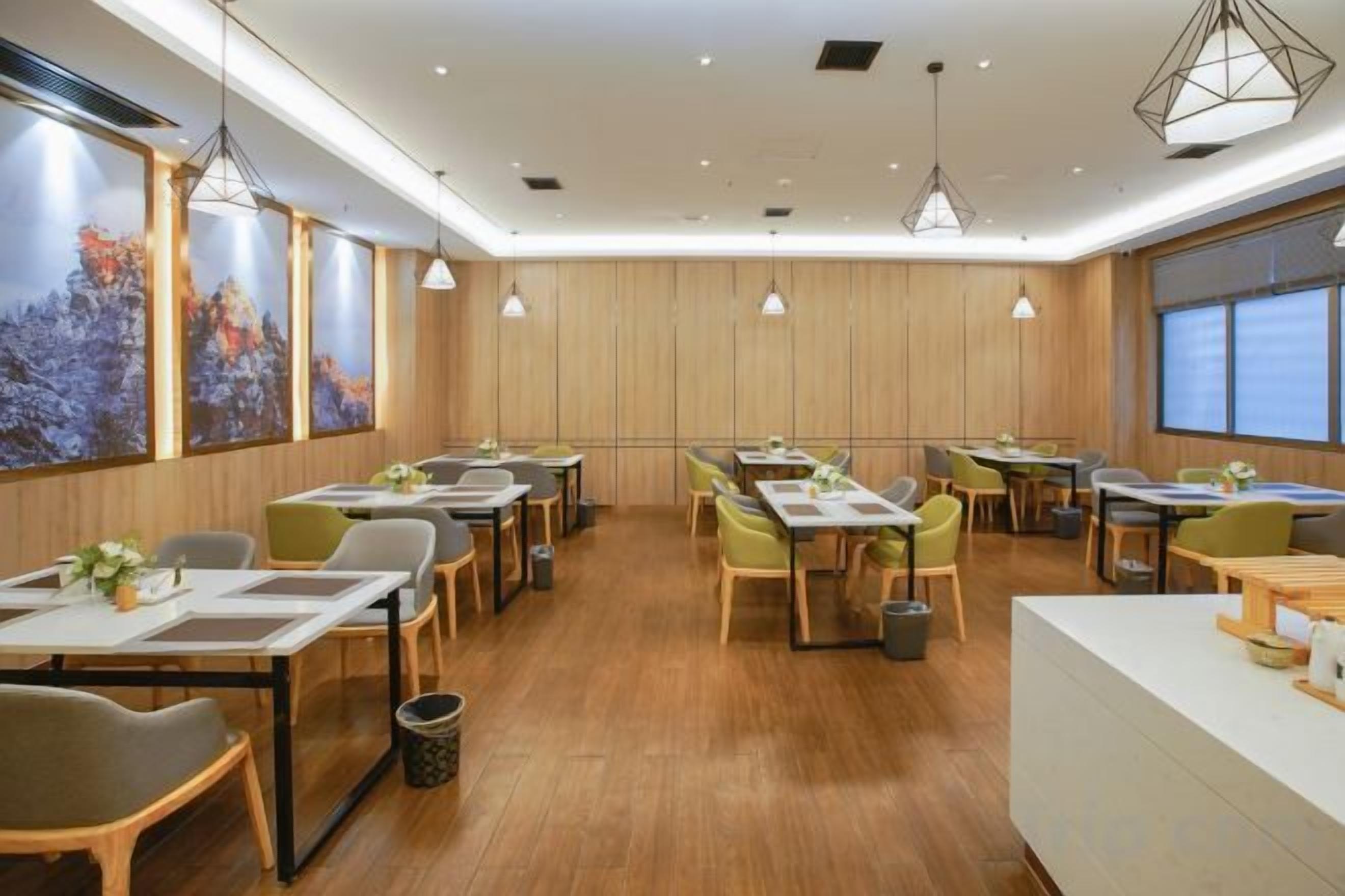 A restaurant with wooden panel walls, multiple tables and chairs, pendant lighting, and large windows.