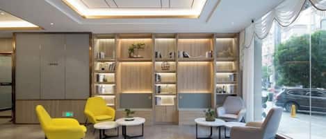 A modern lobby with seating, bookshelves, and a large window.