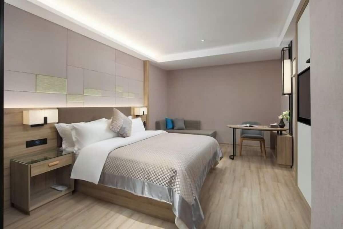 A modern hotel room with a large bed, bedside tables, a desk, and a television.