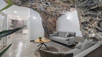 Una sala de estar moderna con un sofá gris, una mesa de centro redonda y una gran formación rocosa.
