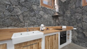 A kitchen with a stone wall, wooden countertop, white sink, and built-in oven. - Luxury House 'La Cueva del Guanche' with Sea Views, Private Pool & Wi-Fi (Adeje)
