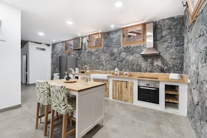 Une cuisine moderne avec un mur d’accent en pierre, un plan de travail en bois et des appareils électroménagers intégrés.