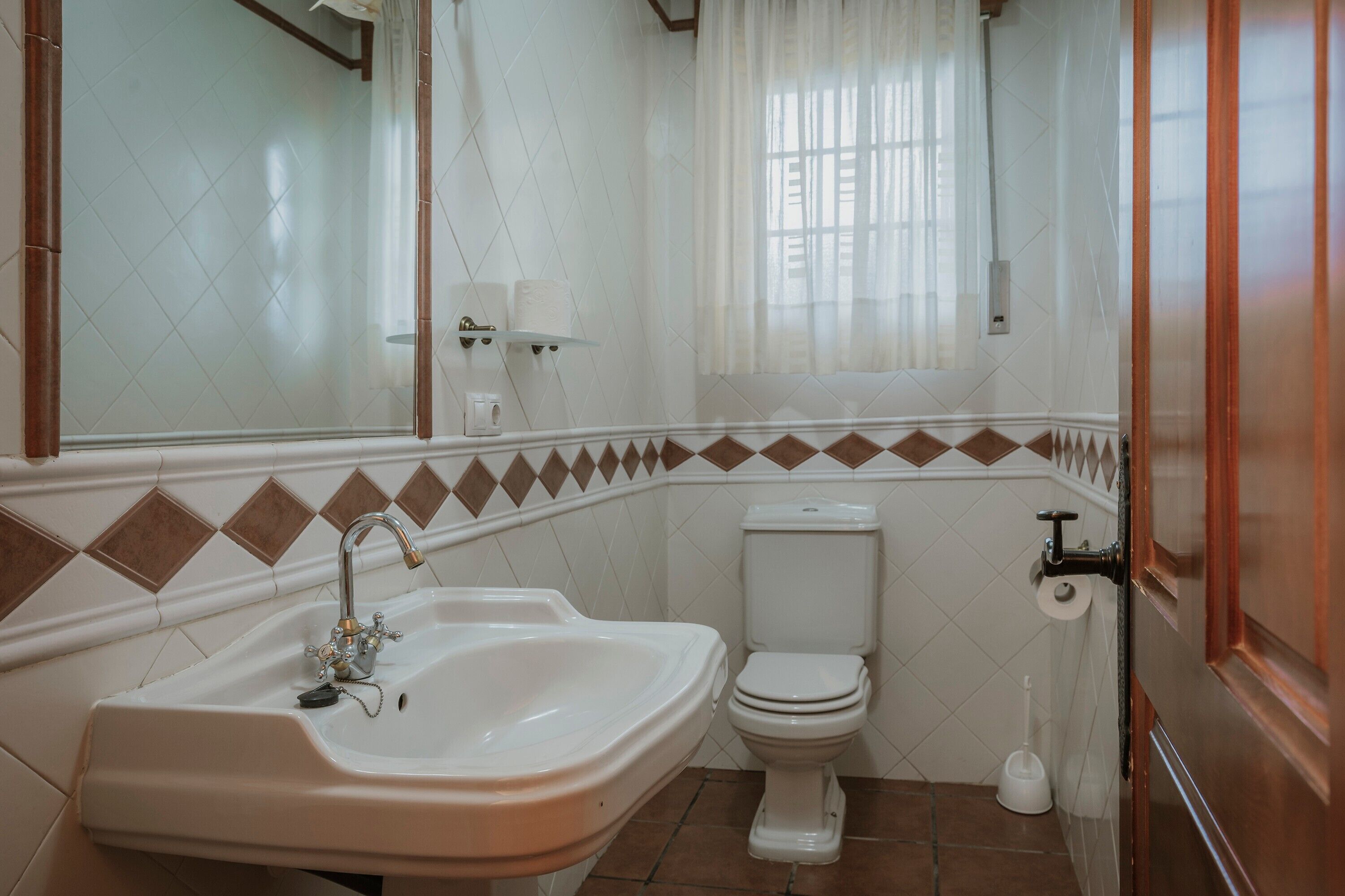 A bathroom with a sink, toilet, and a mirror.