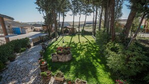 Un sendero de piedra conduce a una zona verde con macetas y una pequeña construcción de madera.