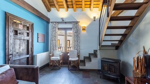 A cozy interior with a wooden staircase, a fireplace, and a dining area with chairs. - Apartment 'Alojamiento Taurus' with Balcony and Wi-Fi (Braojos de la Sierra)
