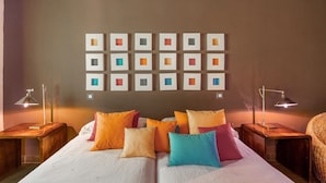 A bedroom with a bed, pillows, bedside tables, and wall art. - Country House 'Alojamiento Perseus' with Mountain View, Balcony and Wi-Fi (Braojos de la Sierra)