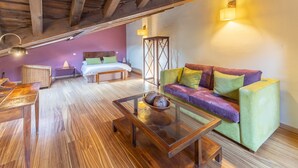A cozy room with a wooden ceiling, a green sofa, a wooden coffee table, a bed with pillows, and a bedside table. - Country House 'Alojamiento Perseus' with Mountain View, Balcony and Wi-Fi (Braojos de la Sierra)