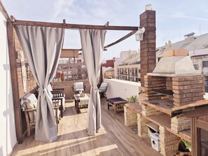 A rooftop terrace with a brick oven, wooden furniture, and a view of the cityscape. - Holiday Home 'Oasis De Valencia' with Private Terrace, Wi-Fi and Air Conditioning (Valencia)