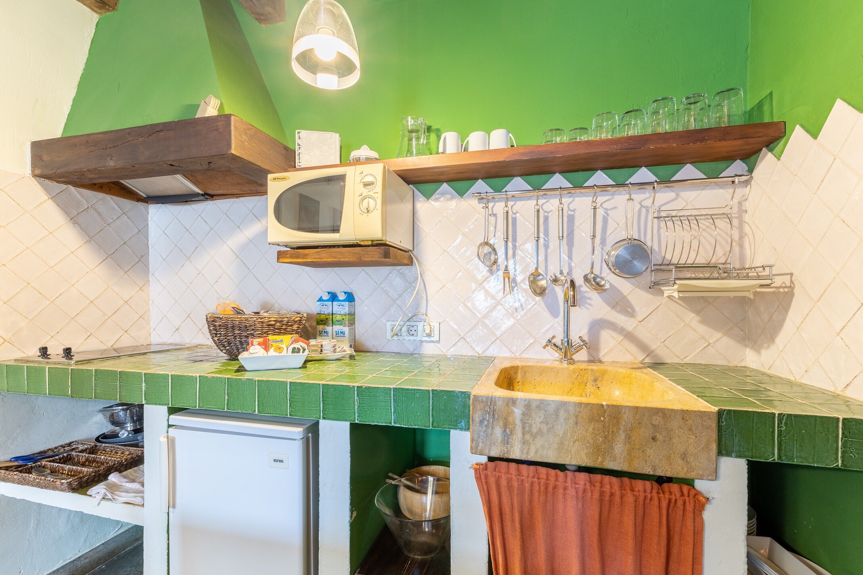 Una cocina con microondas, lavamanos y diferentes utensilios.