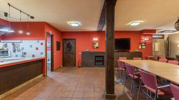 Un restaurante con una larga mesa de madera, paredes rojas y piso de baldosas.