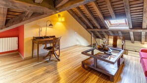 A loft bedroom with exposed wooden beams, a skylight, a dining table, and a red wall. - Country House 'Alojamiento Hercules' with Mountain View, Balcony and Wi-Fi (BRAOJOS)