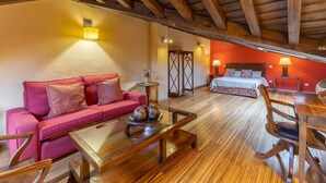 A cozy room with a wooden ceiling, a red sofa, a wooden coffee table, and a bed with a red wall in the background. - Country House 'Alojamiento Hercules' with Mountain View, Balcony and Wi-Fi (BRAOJOS)