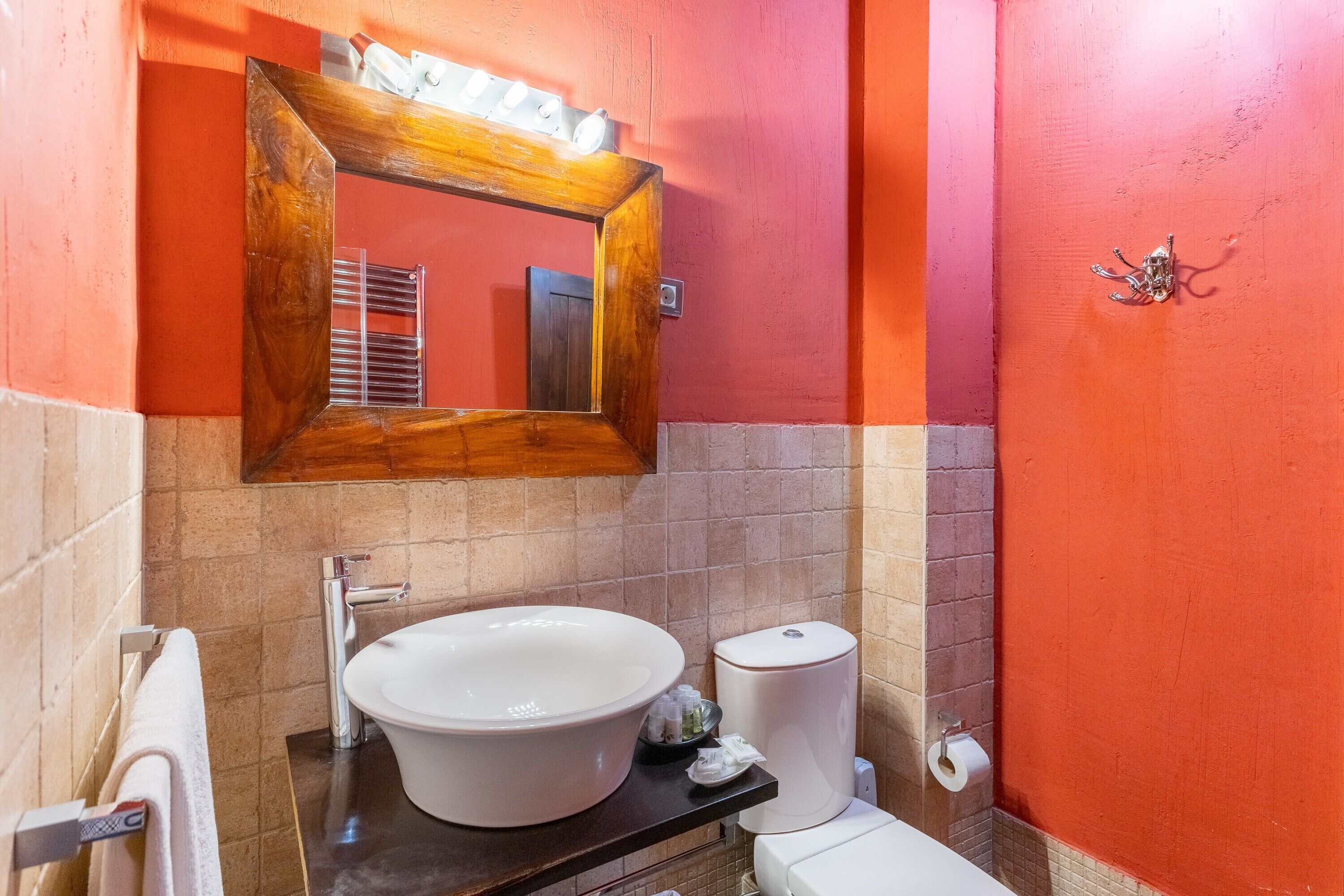 Une salle de bain avec un lavabo blanc, un miroir et des toilettes.