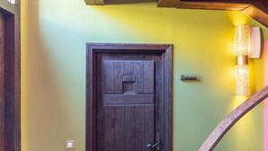 Een houten deur met een klein raam, een lichtschakelaar en een wandlamp.