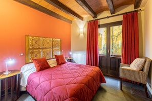 A bedroom with a large bed, a wicker chair, a decorative headboard, and a window with curtains. - Country House 'Alojamiento Andromeda' with Mountain View and Wi-Fi (Braojos de la Sierra)