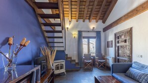 A living room with a wooden staircase, a sofa, a table, and a decorative vase. - Country House 'Alojamiento Pegasus' with Mountain View, Balcony and Wi-Fi (Braojos de la Sierra)
