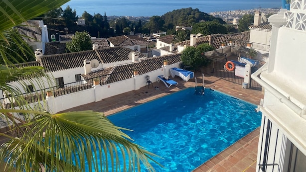 A rooftop pool with a view of the sea and cityscape.