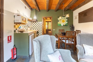 A kitchen with a microwave, a sink, and a fire extinguisher. There is a dining area with a table and chairs.