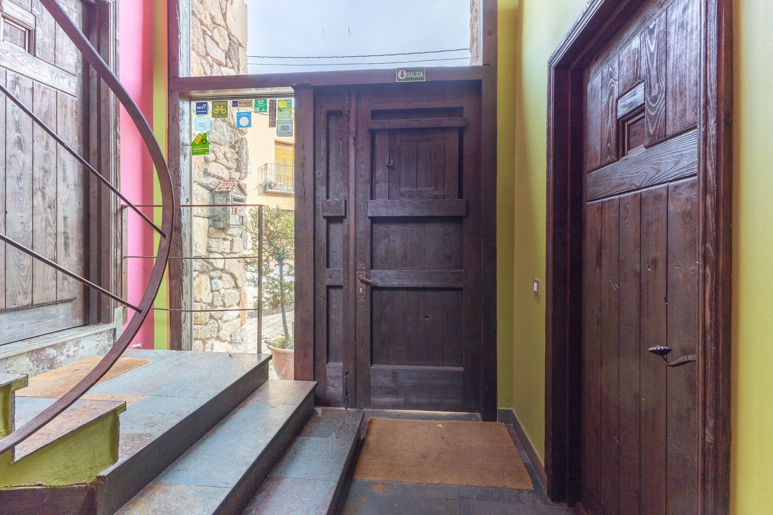 A wooden door with a sign above it, a set of stairs leading up to the door, and a stone wall in the background.