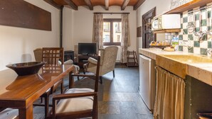 A kitchen with a wooden table, chairs, a television, and a sink.