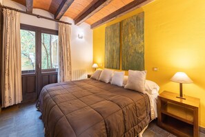 A bed with a brown quilt, a wooden nightstand with a lamp, and a window with curtains.