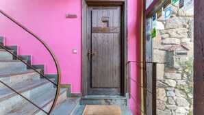 A wooden door with a metal handle, a stone wall, and a pink wall.