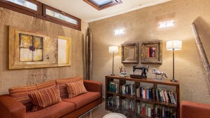 A living room with a sofa, a glass coffee table, a bookshelf, and two wall-mounted lamps.