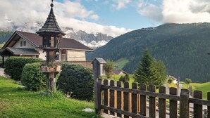 A mountain lodge with a wooden fence, a bell tower, and a view of snow-capped mountains. - Apartment 'Villa Solinda App Vivaldi' with Mountain View, Private Terrace and Wi-Fi (Selva)