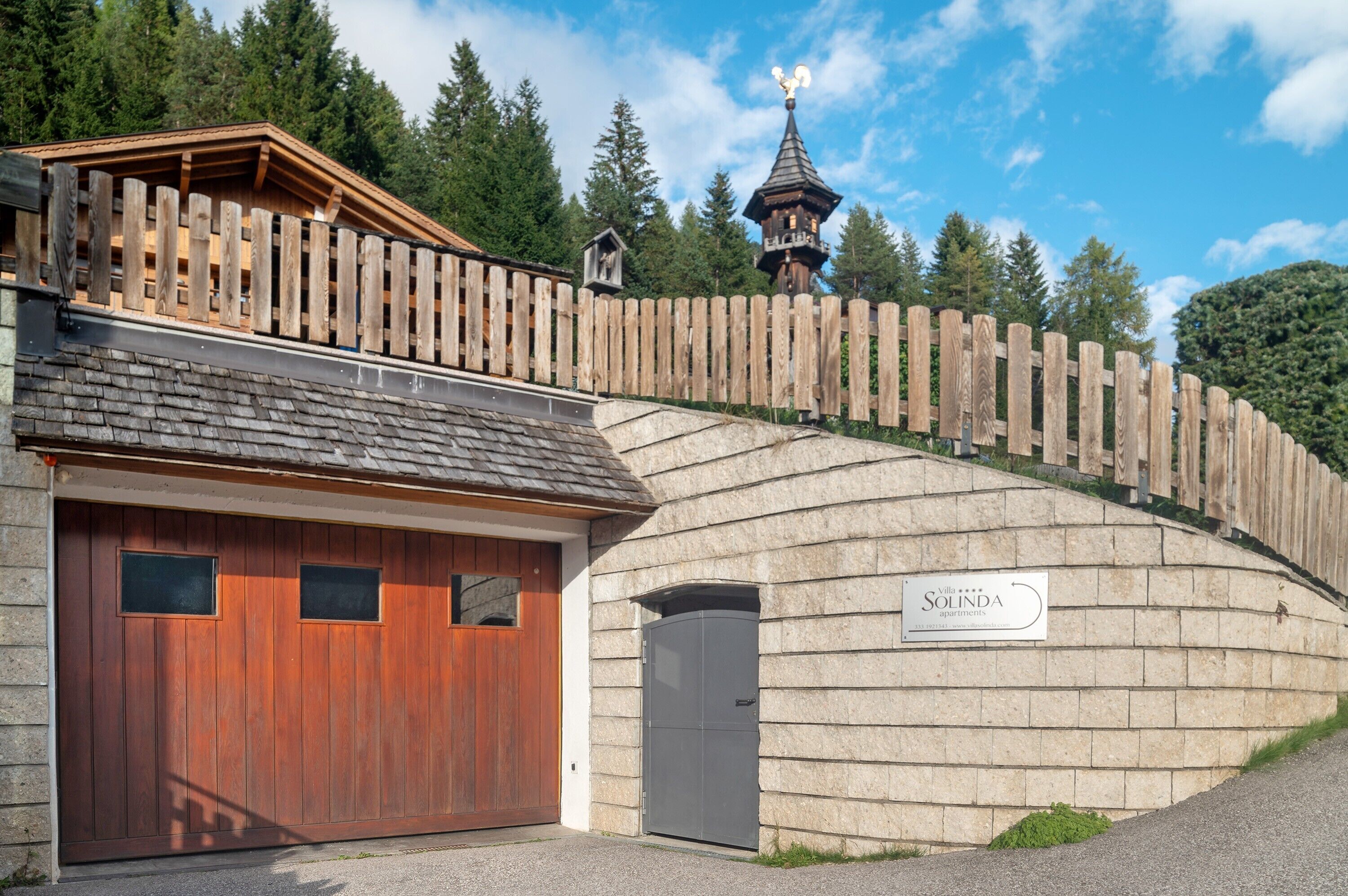 Un edificio con recinzione in legno, un garage e un cartello con la scritta 'Solinda'.