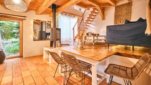 A wooden interior with a staircase, a dining area with chairs, a sofa, and a large window. - Holiday Home 'L'atelier M' with Mountain View, Private Terrace and Garden (Quaix-en-Chartreuse)