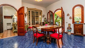 Een eetruimte met een houten tafel, rode fauteuils en een vloer van blauwe tegels.