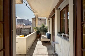 A narrow balcony with a tiled floor, a potted plant, a bench, and a radiator.