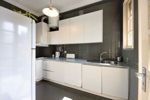 A modern kitchen with white cabinets, a granite countertop, a stainless steel sink, and a hanging light fixture.