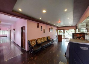 A hotel lobby with a reception desk, a black leather sofa with patterned cushions, and a large water dispenser. - Green Park Gran Inn (Kodaikanal)