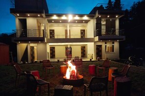 A two-story building with a fire pit in the center surrounded by chairs. - Green Park Gran Inn (Kodaikanal)