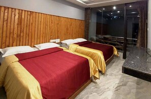 A hotel room with two beds, a wooden headboard, a marble floor, and a balcony with a view. - Green Park Gran Inn (Kodaikanal)