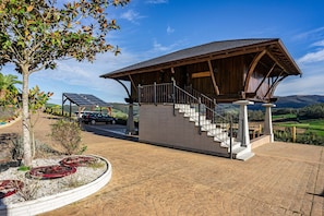 A building with a wooden exterior, a staircase leading to a covered area, and a solar panel in the background.