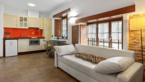 A compact living space with a kitchenette, a sofa, a dining table, and a lamp.