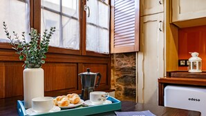 Un plateau de petit-déjeuner avec des croissants, une cafetière et une tasse, posé sur une table en bois.