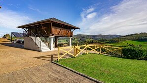 Une structure en bois avec un escalier menant à une zone abritée, des panneaux solaires et une vue sur des collines verdoyantes.