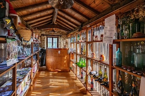 A rustic interior with wooden shelves, a central barrel, and various bottles.